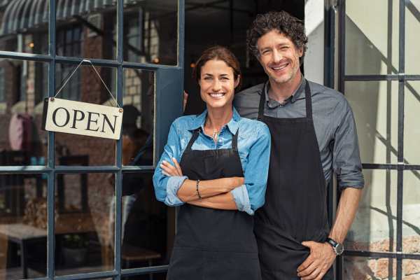 A man and a woman smiling in front of their business