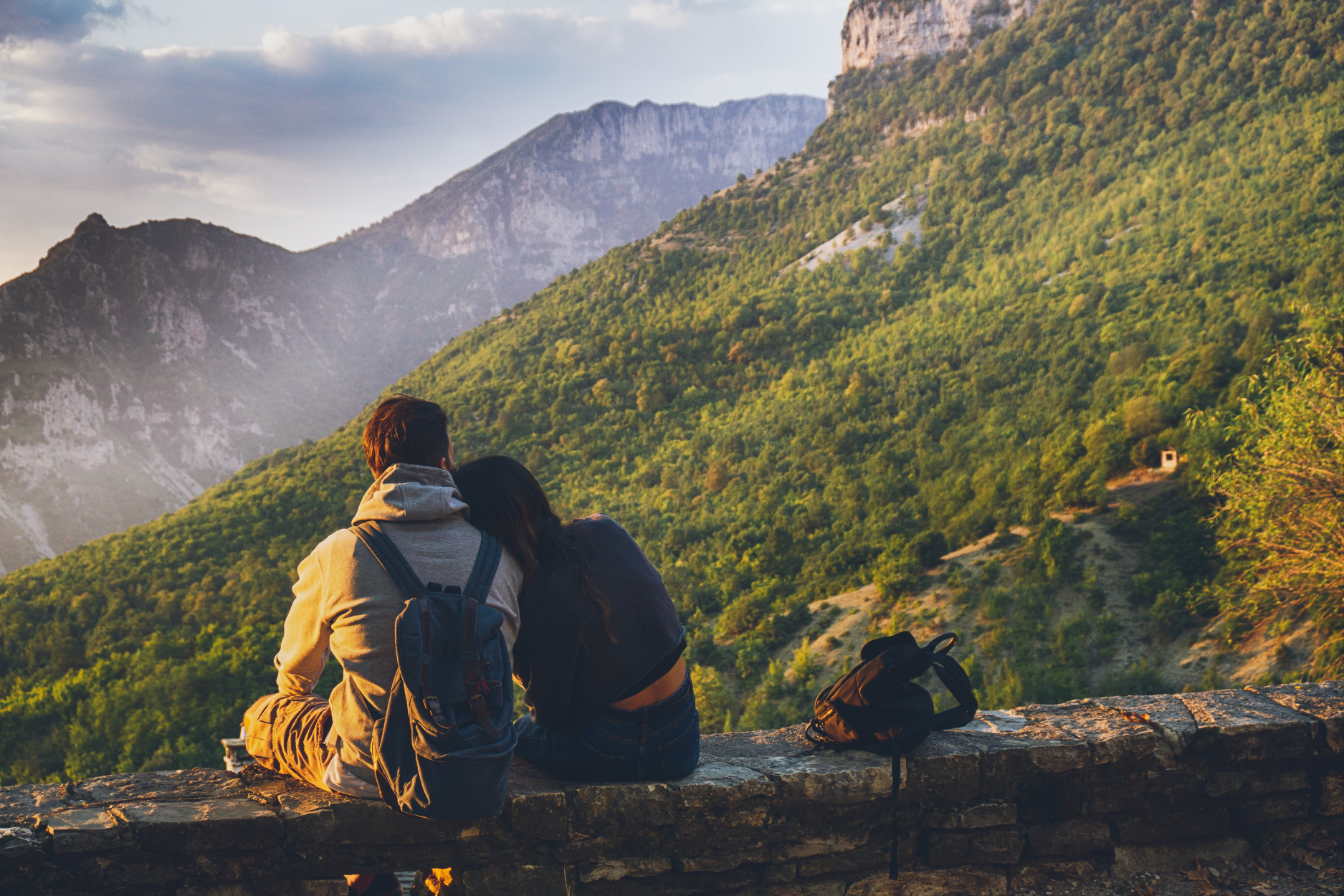 Couple sitting on an overlook enjoying a mountain view.